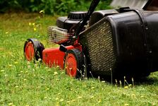 A red lawnmower cutting grass